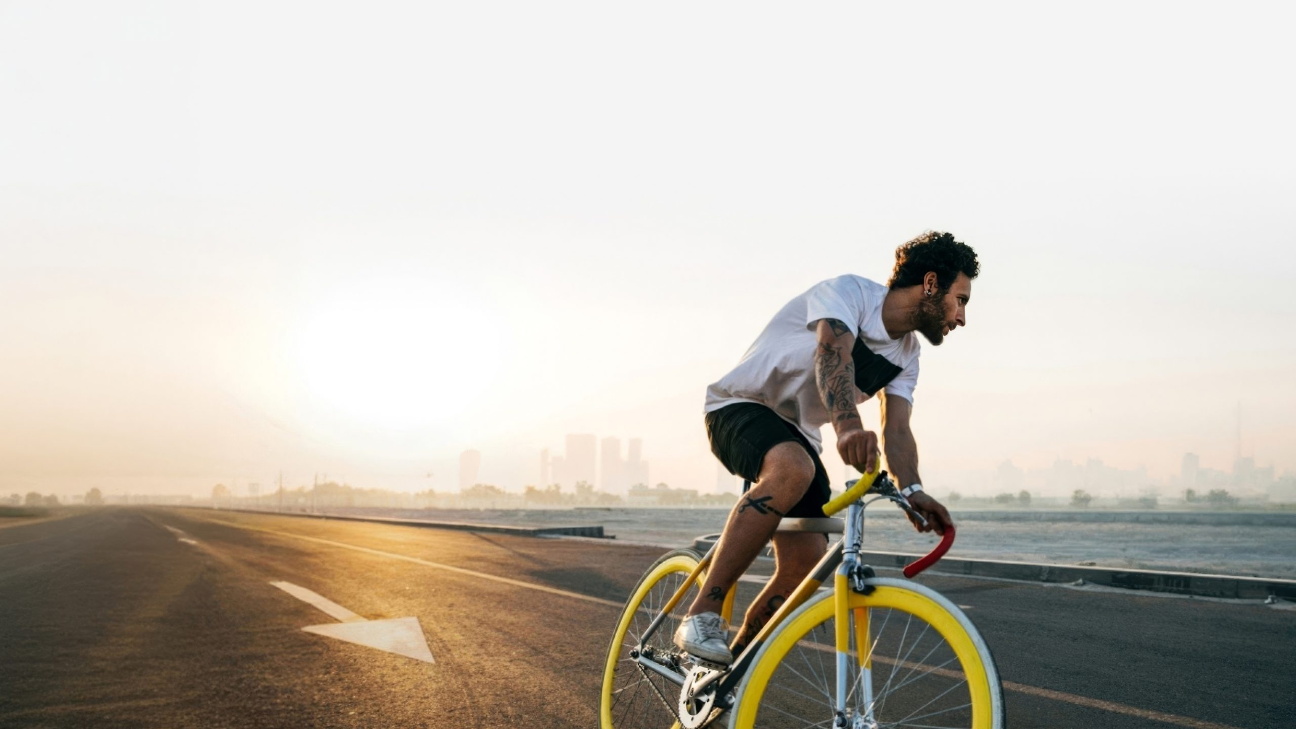 Cyclist riding toward a golden sunset on the horizon